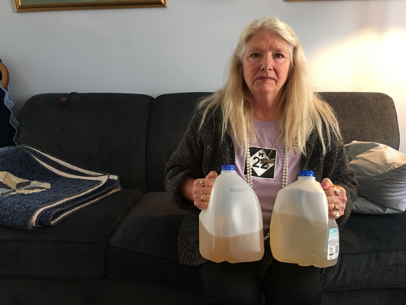 Gladyes Williamson holds up two water jugs full of water from the tap at her Flint home. Photo: Ryan Felton
